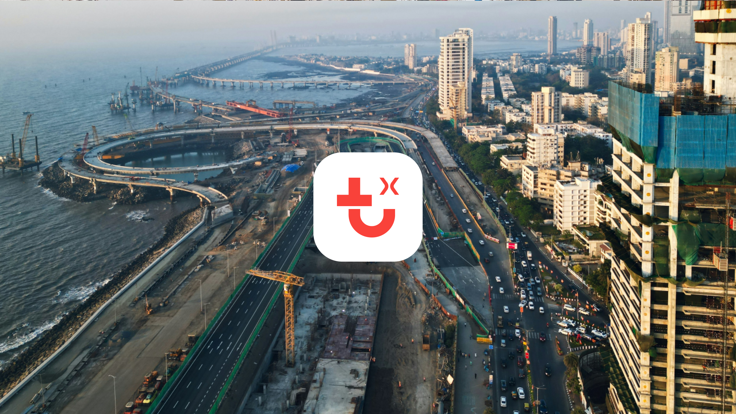 Aerial view of a coastal city with high-rises, busy road, ongoing construction, and shoreline. IrisX app icon overlaid center.