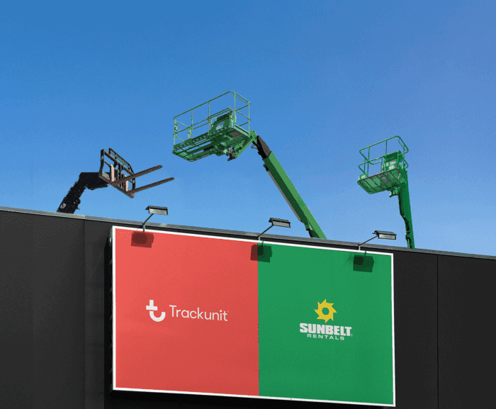 Three elevated work platforms rise above a black building with Sunbelt Rentals sign and Trackunit logo under a clear blue sky.