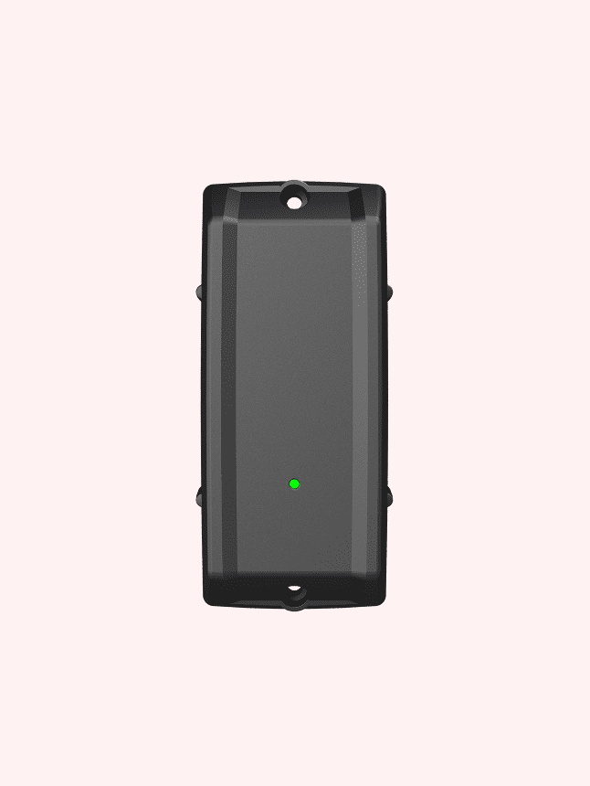 A black rectangular device with a green LED indicator, mounted vertically, used for construction equipment tracking.