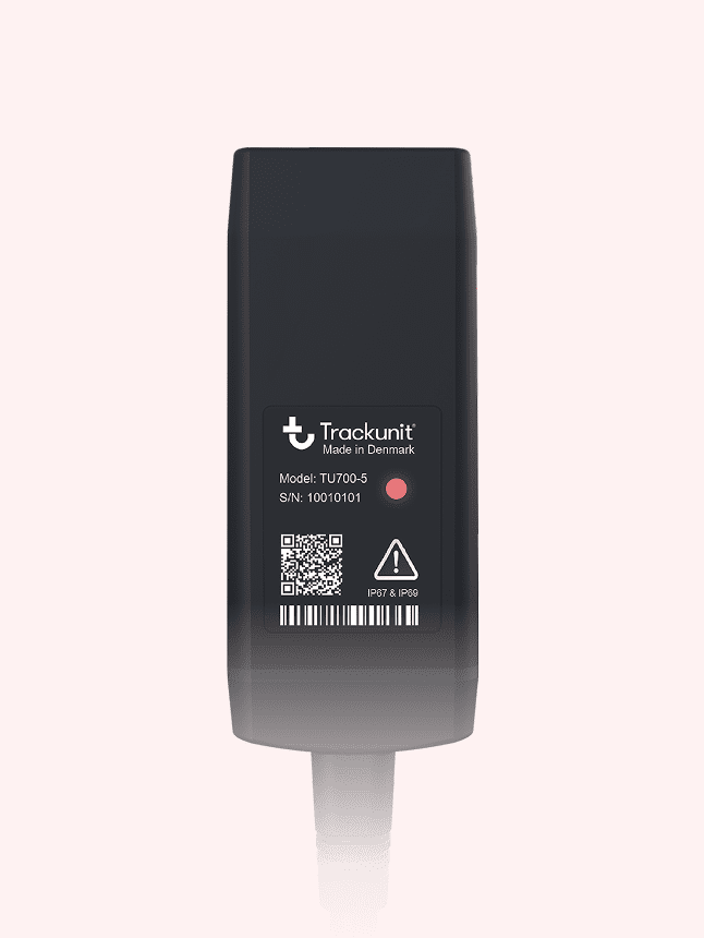 A black Trackunit TU7100-S device with QR code, barcode, and serial number label for construction equipment tracking.