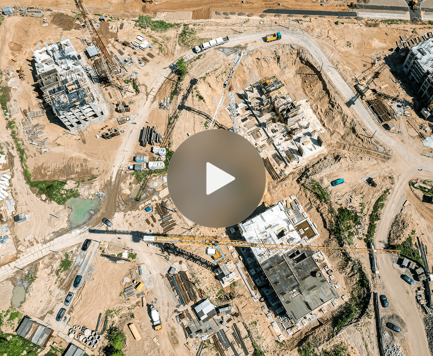 Aerial view of a construction site with vehicles, equipment, dirt roads, and buildings in progress, showing a connected jobsite.