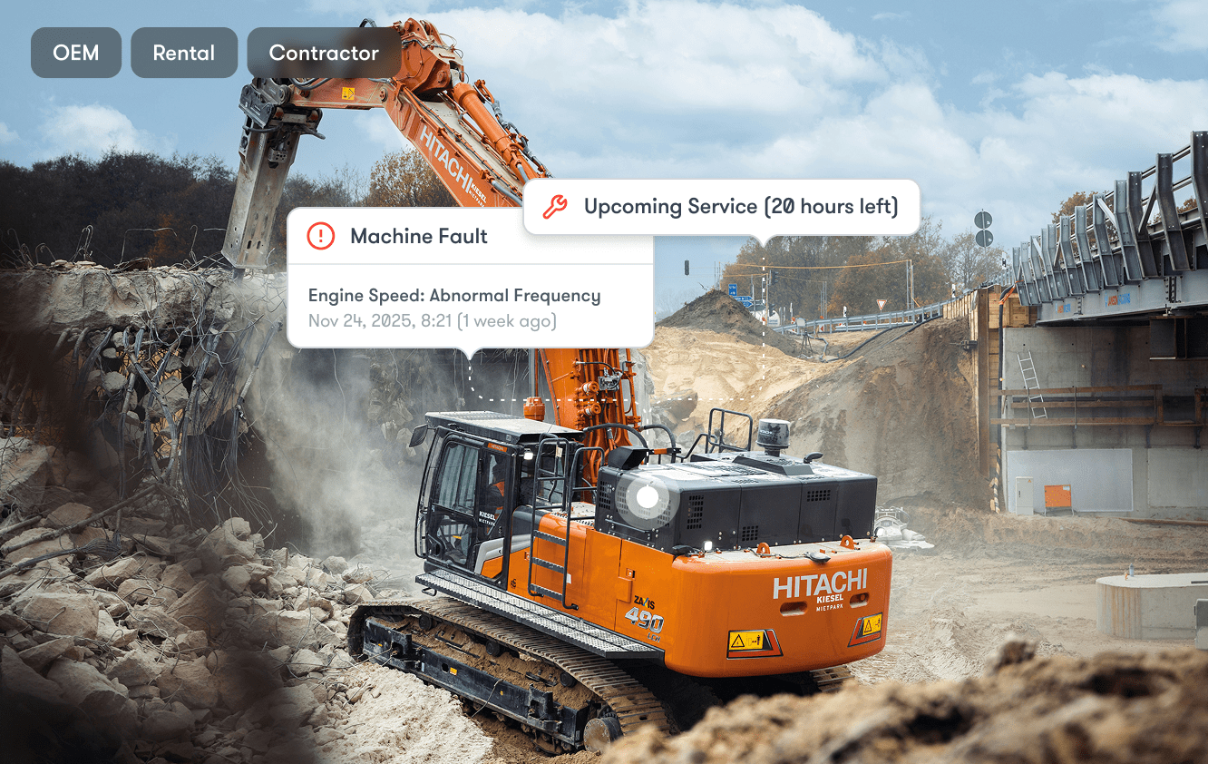 An orange Hitachi excavator at a construction site displays digital machine alerts, highlighting connected jobsite technology.