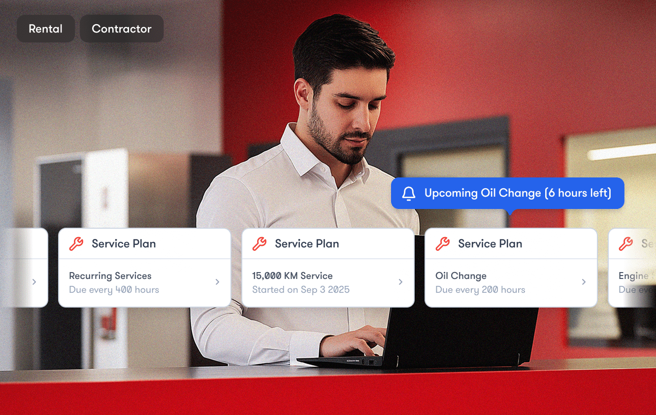 A man in a white shirt uses a laptop at a red desk, managing vehicle maintenance online—an example of fleet management.