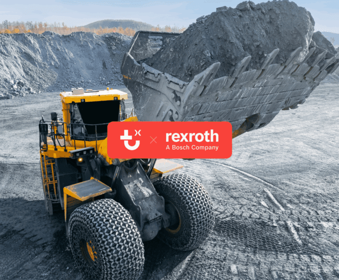 A large yellow wheel loader lifts dirt at a mining site, with rocky terrain, Rexroth logo, and Trackunit IrisX technology overlay.