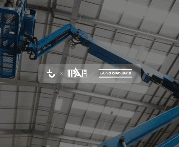 A blue boom lift extends toward the ceiling in a large industrial building; IPAF and Laing O'Rourke logos are centered on the image.