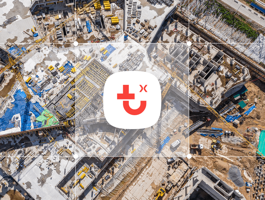 Aerial view of a busy construction site with scattered equipment, overlaid by an app icon showing a red smiley and medical cross.