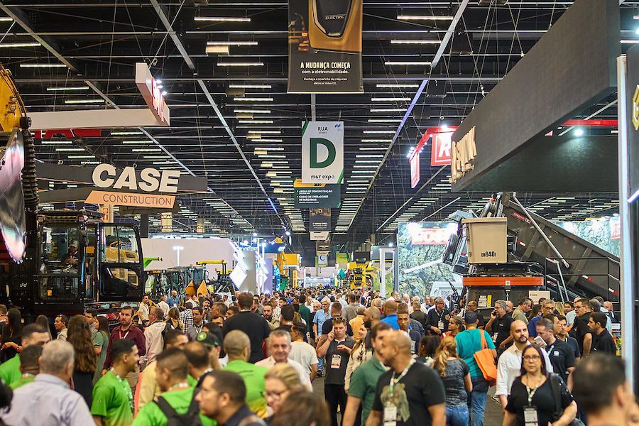 Crowds walk through a busy trade show with construction equipment, machinery, and booths focused on construction equipment tracking.