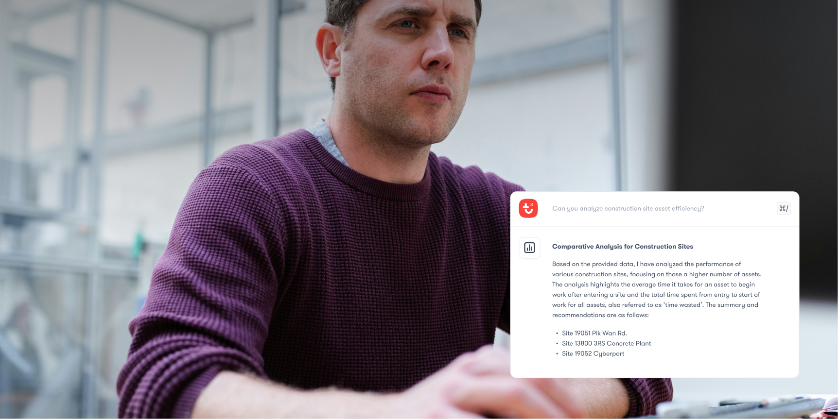 A man in a maroon sweater reviews a computer screen showing a construction site report and recommended installs, highlighting connected jobsite.