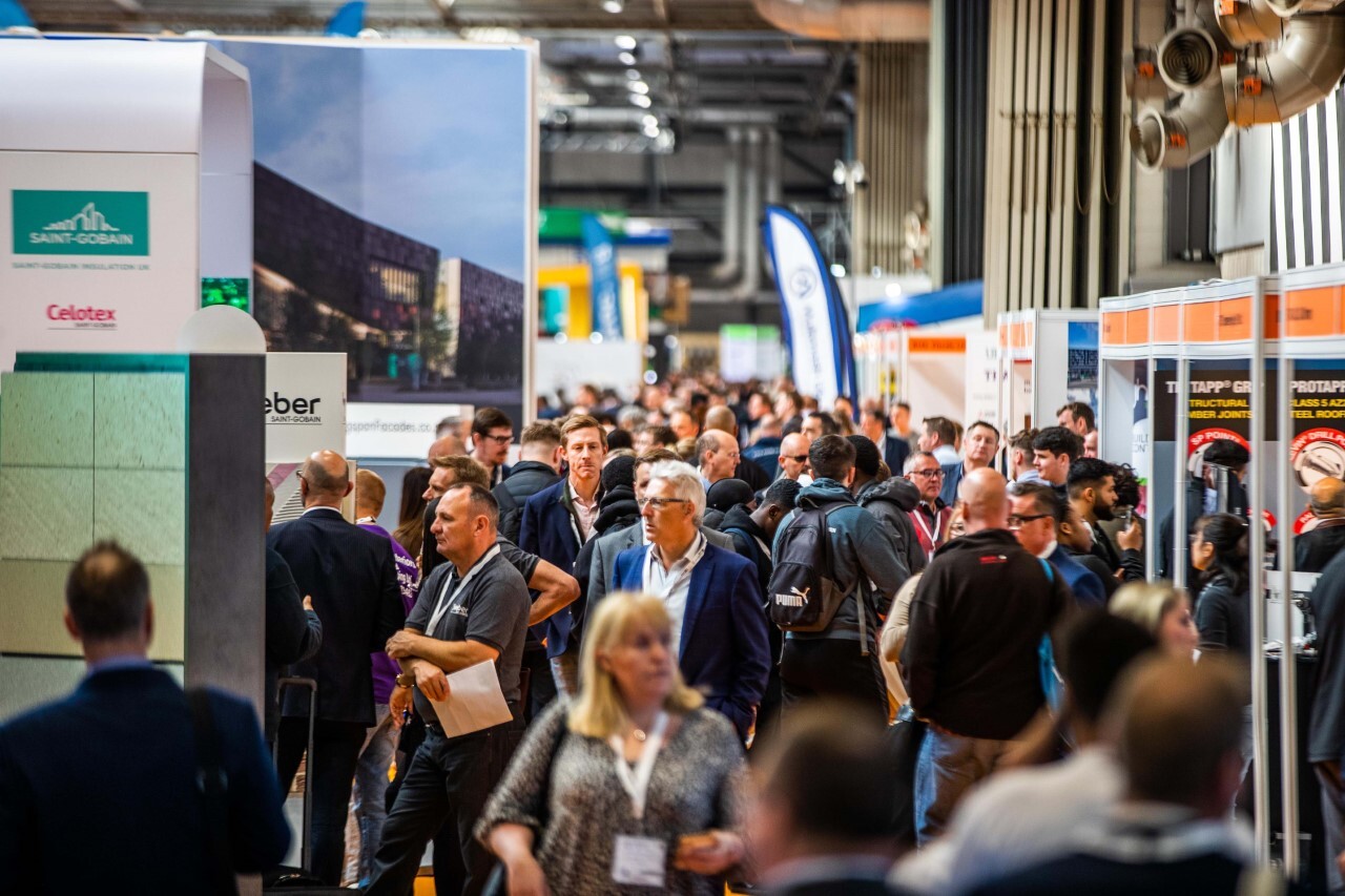 Crowds walk through a busy UK Construction Week 2026 exhibition hall, visiting booths focused on construction and connected jobsites.