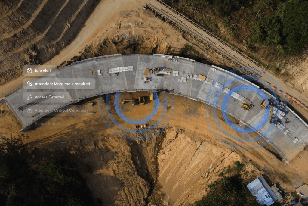 Aerial view of a curved road under construction with heavy machinery and icons showing alerts and updates for connected jobsite progress.