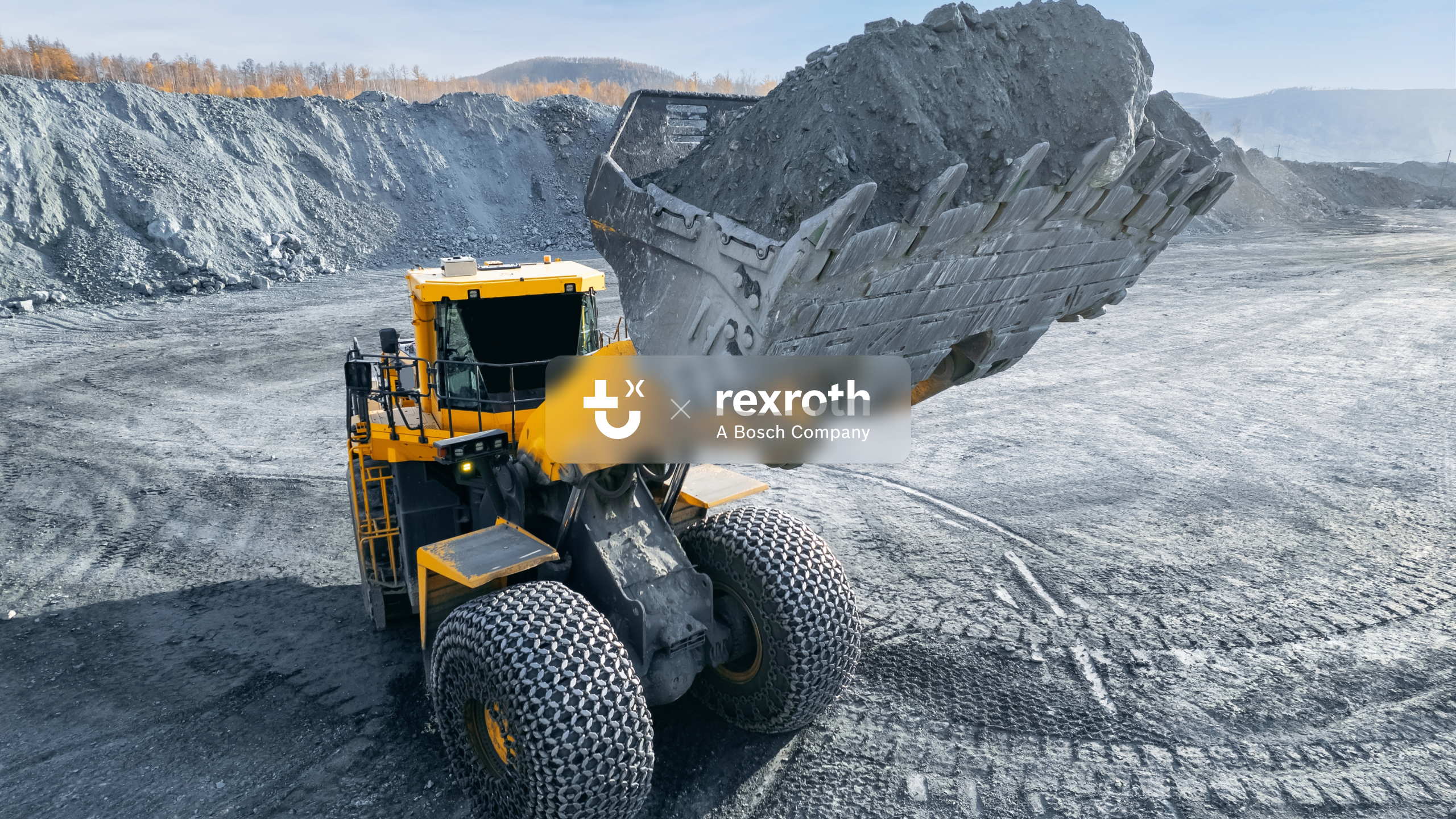 A large yellow wheel loader with IrisX lifts dirt in a quarry, with rocky terrain, autumn trees, and TuSimple and Rexroth logos visible.