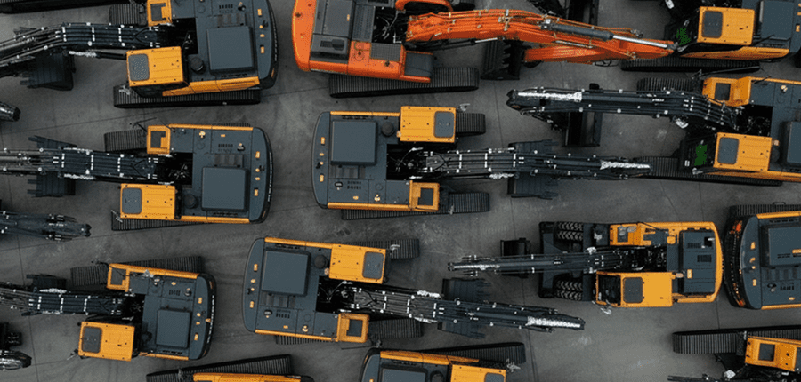 Aerial view of orange and black excavators parked in rows on concrete, their arms extended, illustrating construction equipment tracking.