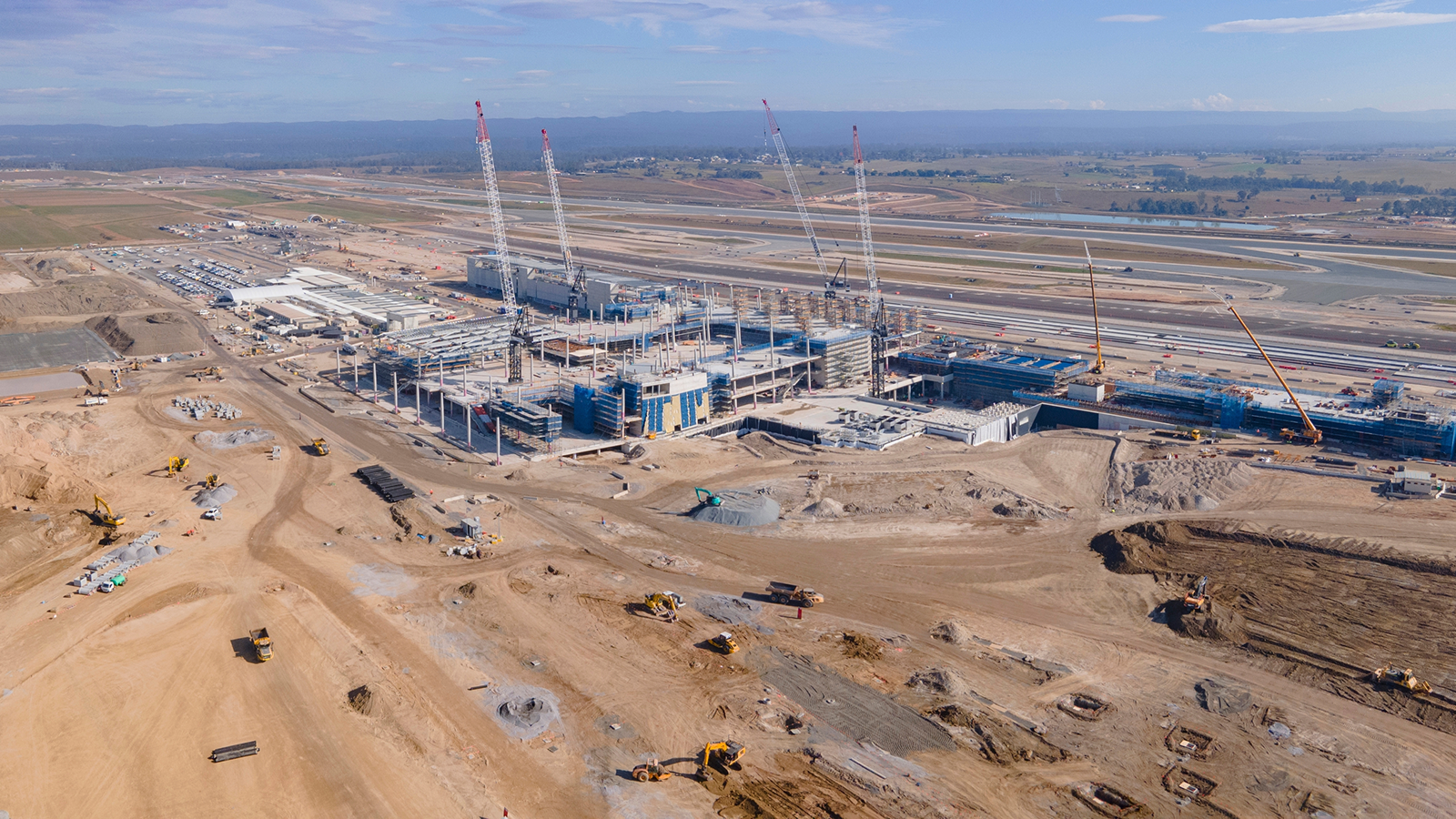 Aerial view of a large construction site with cranes, equipment, and vehicles arranged for efficiency, highlighting fleet management.