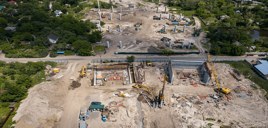 Aerial view of a construction site with cranes, machinery, and building foundations, highlighting fleet management on busy grounds.