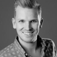 Black and white portrait of a young man in a patterned shirt, smiling at the camera, suitable for construction IoT team profile.
