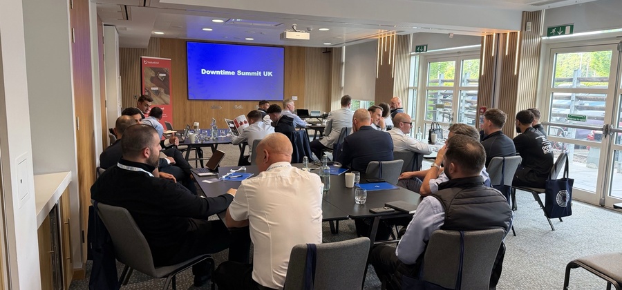 People sit around tables in a conference room at the Downtime Summit UK, taking notes—daylight highlights connected jobsite topics.