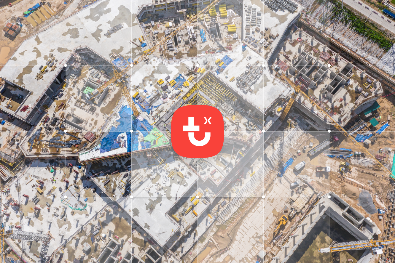 Aerial view of a large construction site with cranes and equipment, featuring a central red plug X icon, suggesting connected jobsite.