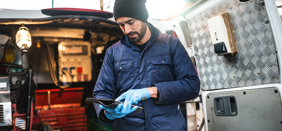 A service technician checks a tablet beside his service van.