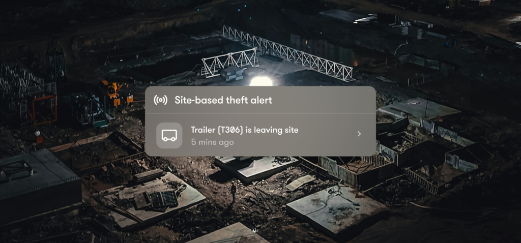 A theft alert on a dark construction site warns that Trailer [T386] left the site 5 minutes ago, with machinery and building materials nearby, illustrating construction equipment tracking.