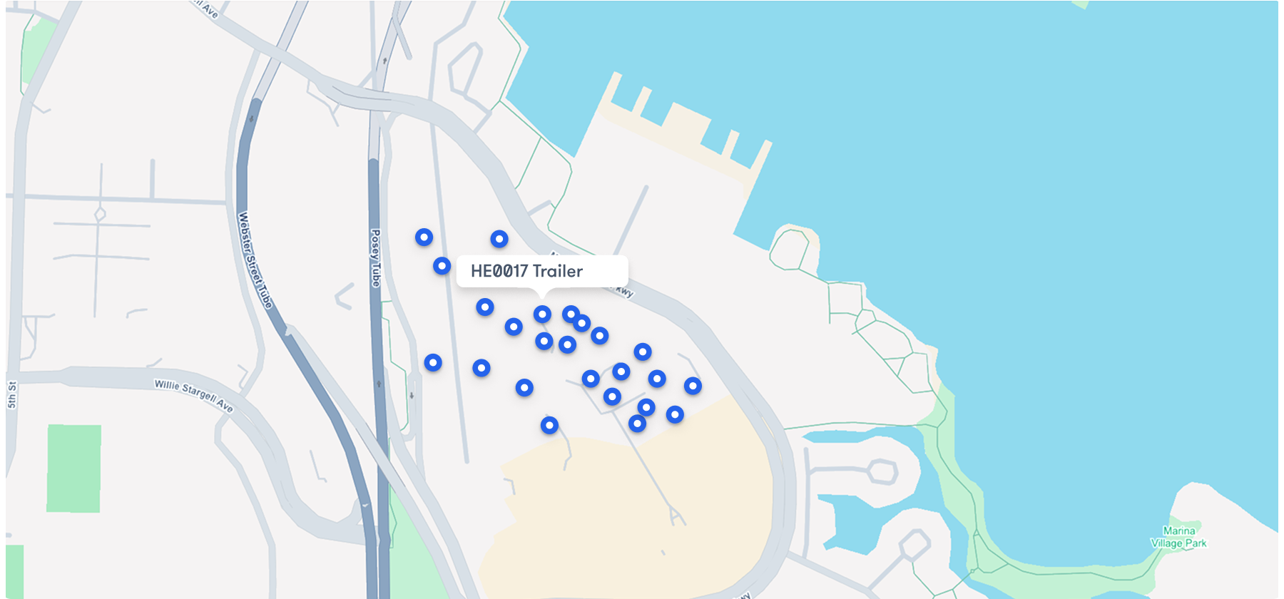 A map displays clustered blue markers around a labeled point, HED017 Trailer, next to a body of water and several roads, highlighting construction equipment tracking.