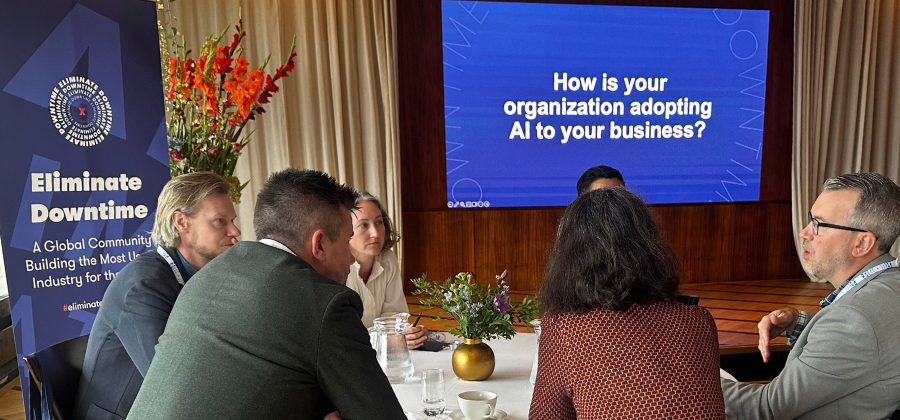 Five people sit around a table discussing AI adoption in business, with a screen showing the question and a banner referencing EU funding for construction in Central and Eastern Europe, suggesting a focus on connected jobsite topics.