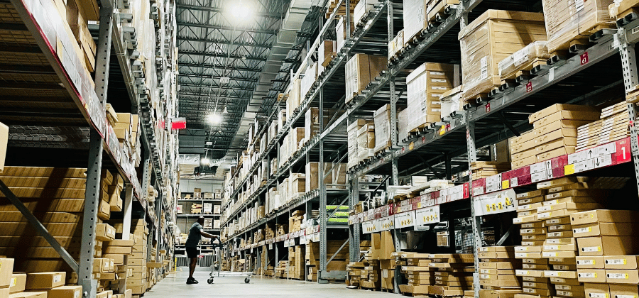 A worker moves stock through a parts warehouse aisle.