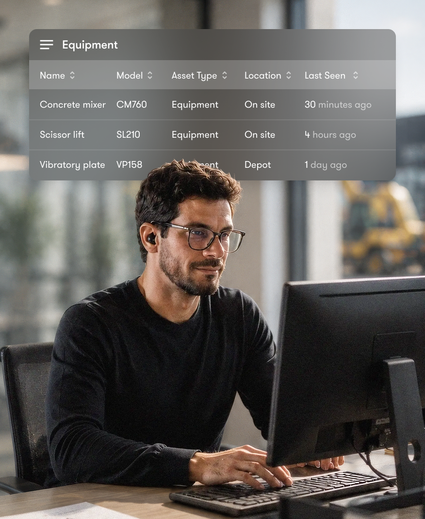 A man using a computer to view a construction equipment tracking dashboard.