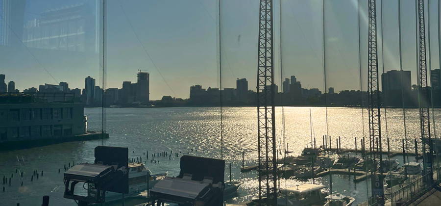 View of a marina and city skyline across the water from behind glass panels.
