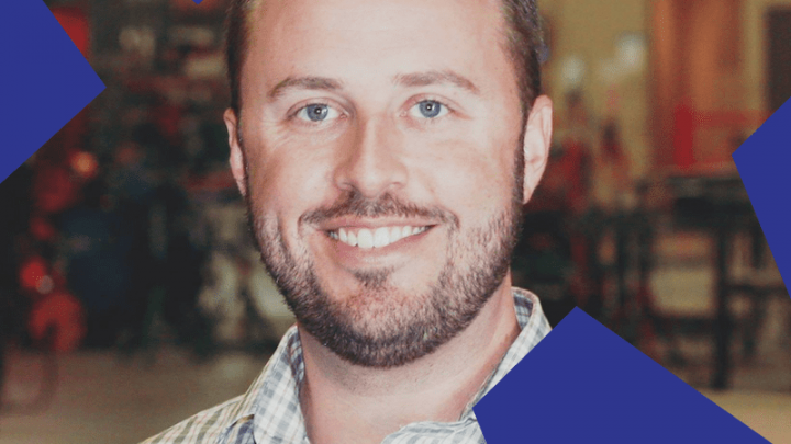 A smiling man in a plaid shirt stands indoors, framed by blue geometric shapes—ideal for a connected jobsite setting.