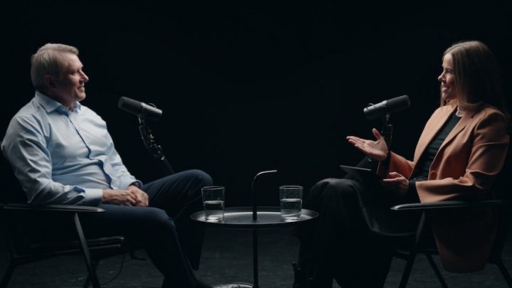 Two people interview each other about The Key to Safe Equipment Access, seated with water glasses and mics, related to construction safety.