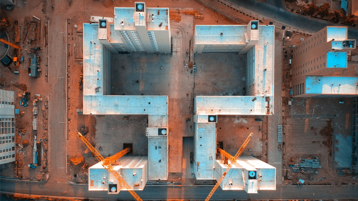 Aerial view of a construction site with two large buildings and yellow cranes, showing efficient connected jobsite coordination.