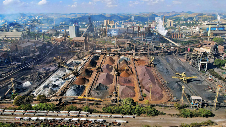 A large industrial site with raw materials, conveyors, cranes, smokestacks, and trains—operations powered by telematics.