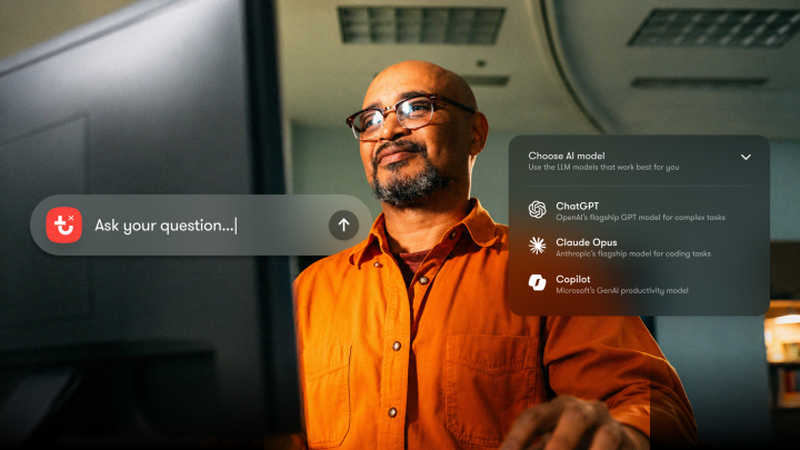 A man in glasses and an orange shirt reviews a floating interface with AI options for analyzing MCP fleet data in a fleet management office.