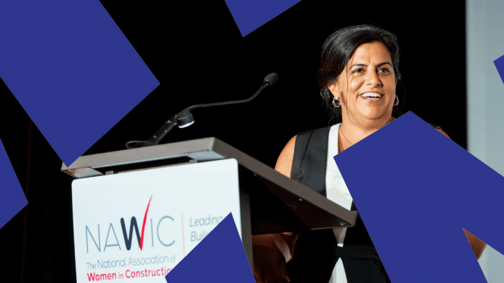 A woman smiles at a podium with a microphone. The NAWIC logo and name are displayed with blue geometric shapes in the background.