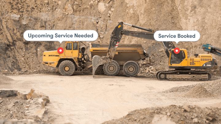 A yellow dump truck and excavator with telematics display maintenance alerts while working in a quarry, highlighting construction IoT.