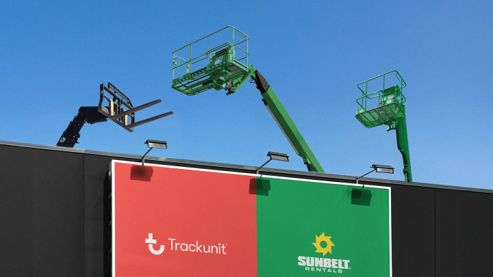 Three elevated work platforms rise above a black building with Sunbelt Rentals sign and Trackunit logo under a clear blue sky.