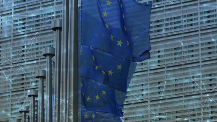 EU flags flutter before a modern glass building with a faint digital network overlay, reflecting policies for construction IoT progress.