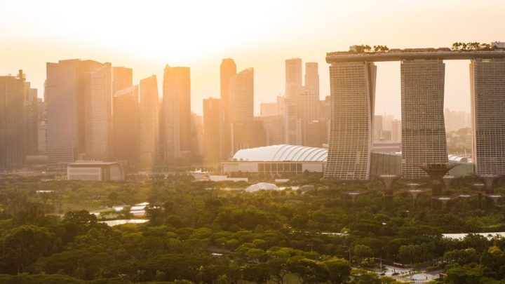 Singapore cityscape at sunset with Marina Bay Sands, modern skyscrapers, lush trees, and glowing sun; ideal for connected jobsite context.