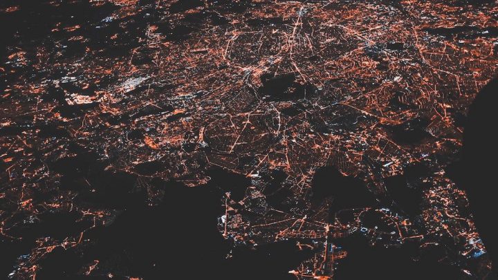 Aerial view of a city at night with glowing streets and highways, evoking connected machines like a connected jobsite network.