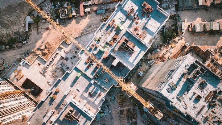 Aerial view of an Asian construction site with several buildings, a large yellow crane, scattered equipment, and construction IoT.