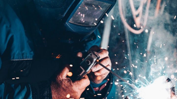 A welder in protective gear works amid sparks and blurred wires, highlighting digital changes in construction and the connected jobsite.