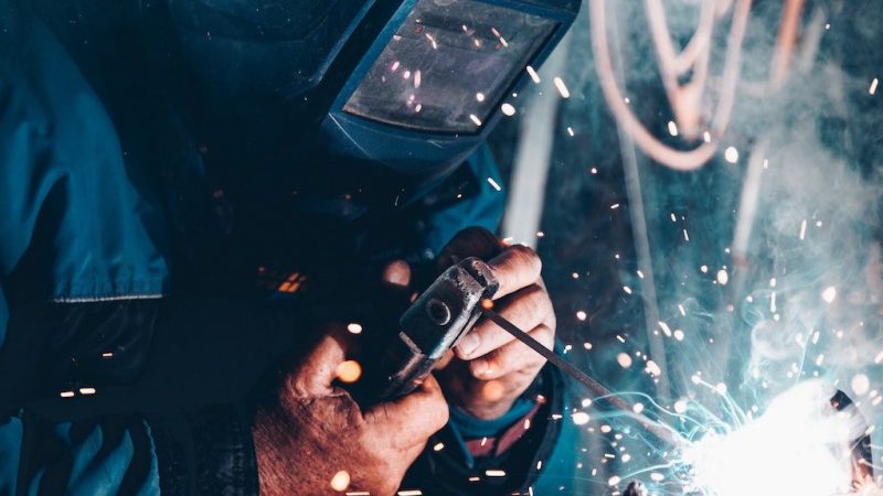 A welder in protective gear works amid sparks and blurred wires, highlighting digital changes in construction and the connected jobsite.