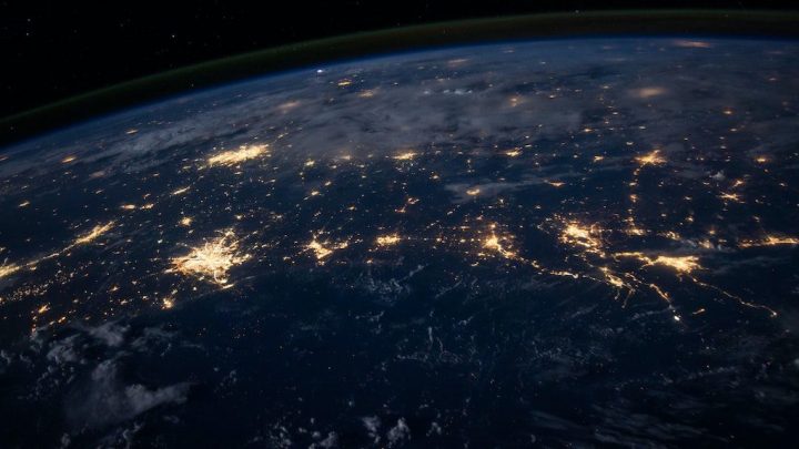 Earth at night from space with city lights and visible construction sites, highlighting global construction equipment tracking.