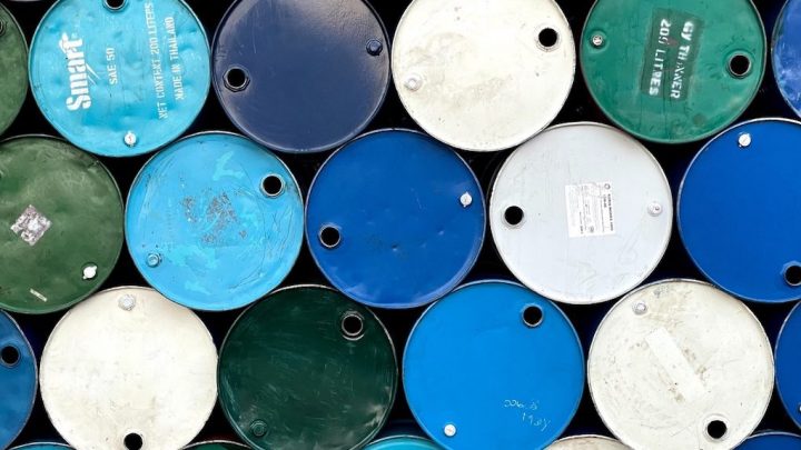 Stacked green, blue, white, and teal industrial barrels viewed from above, lids visible; could support fleet management.