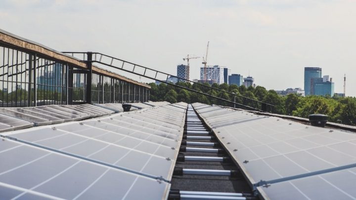 Solar panels on a rooftop with city skyline and construction cranes in the background, highlighting sustainable connected jobsite.