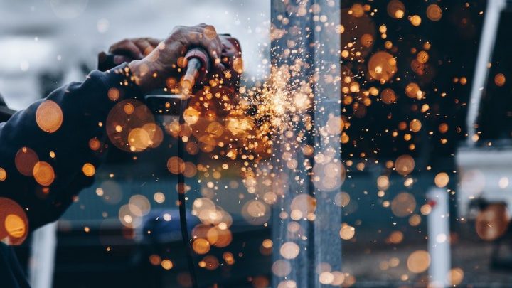 A person uses a power tool to grind metal, sending sparks flying—an inspiring scene on a connected jobsite.