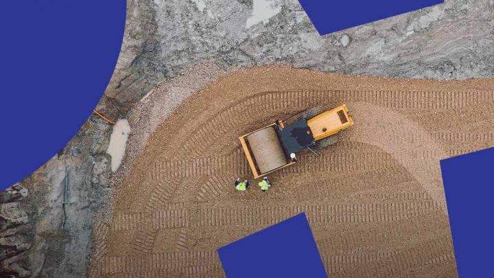 Aerial view of a construction site with a yellow bulldozer and two workers; blue shapes overlay for connected jobsite concept.