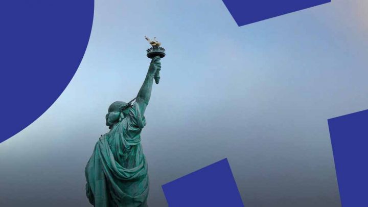 The Statue of Liberty from behind with torch raised, blue shapes overlaying the sky, symbolizing diversity and connected jobsites.