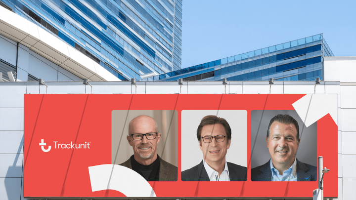 A large billboard on a modern building shows the Trackunit logo and three smiling Board Members in business attire on a red background.