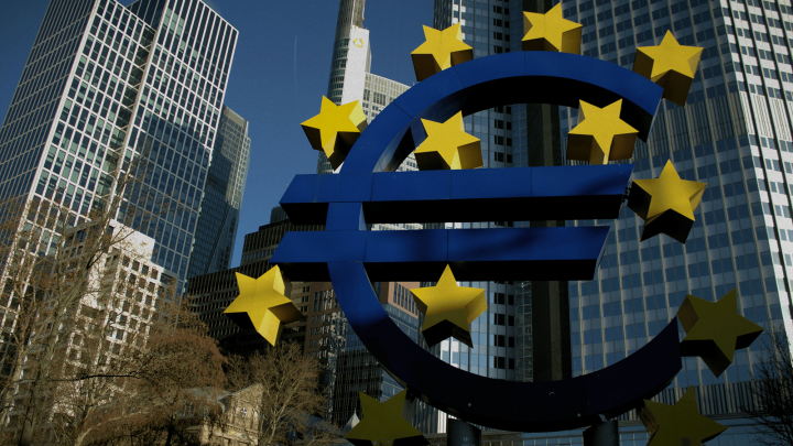Large blue euro symbol with yellow stars in front of modern skyscrapers, illustrating EU funding’s impact on construction and connected jobsites in Central and Eastern Europe, under a clear sky with trees at the bottom left.